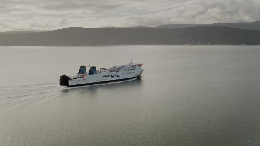 A ferry moves slowly through the sea as birds fly overhead