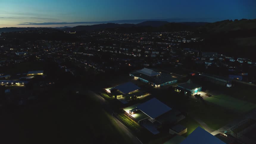 A dense neighborhood below tall hills is lit up at night