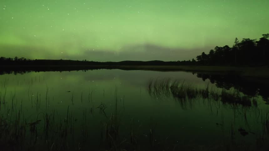 Time-lapse of northern lights and a shooting star over a lake