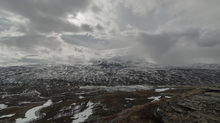 Clouds blowing over snowy spring mountains