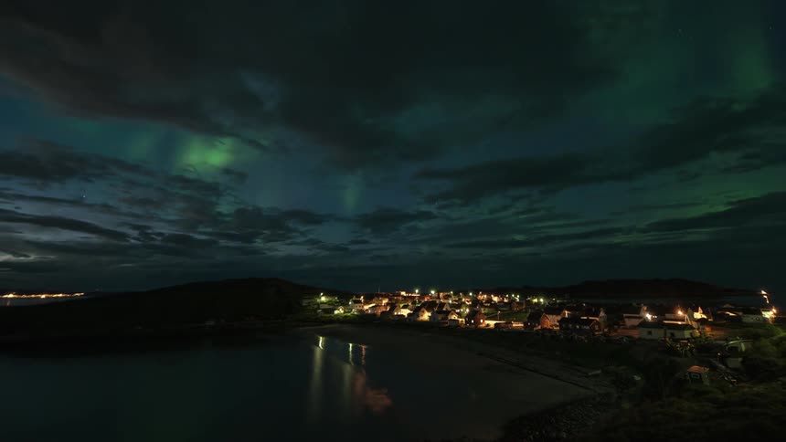 Timelapse of clouds and aurora borealis moving over a city