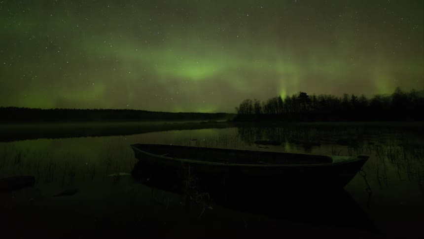 The northern lights over a wooden row boat on water