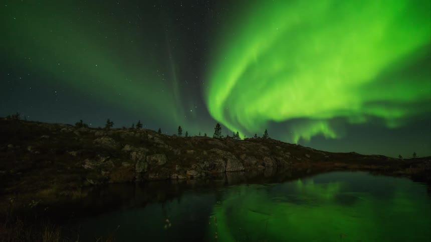 Streaming aurora borealis over a small freezing lake