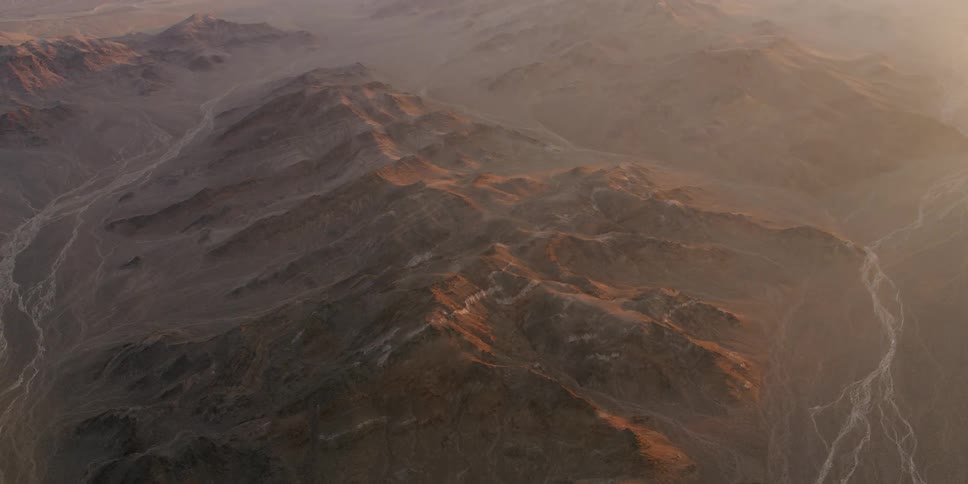 Brown rocky mountain ridges with veins of water snaking down the slopes