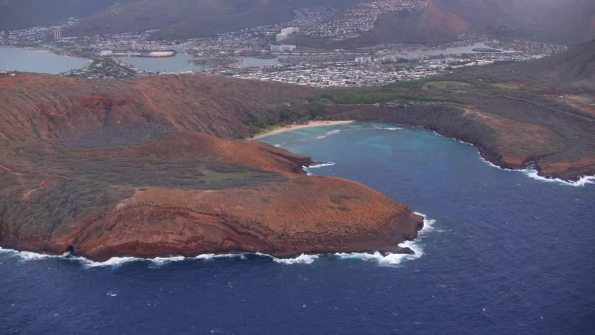 The ocean meets a shoreline with a cove in which an inviting beach is situated