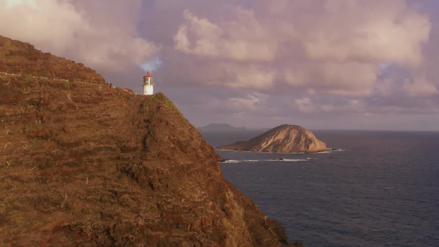 A lighthouse sits on the edge of a cliff over the ocean