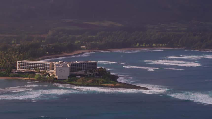 An office building made of three long sections sits on a peninsula along the coast