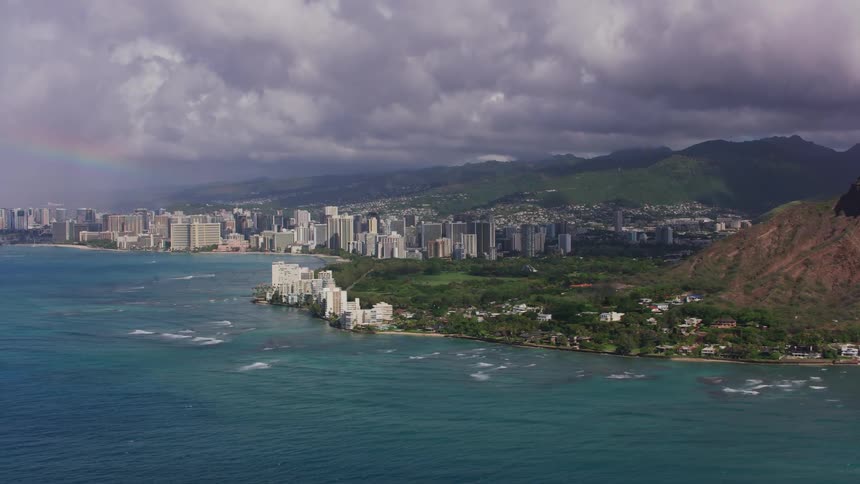 A coastal city skyline with mountains and ridges on a cloudy day