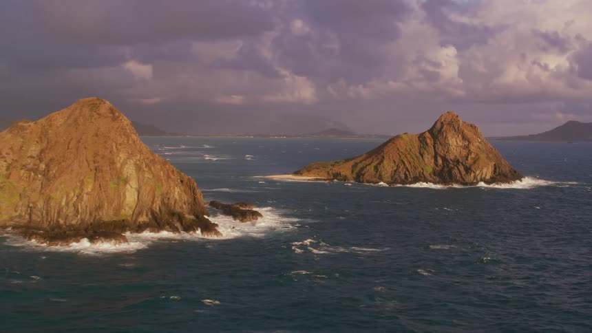Overcast sky hovers over foggy horizon and waves crashing against islands