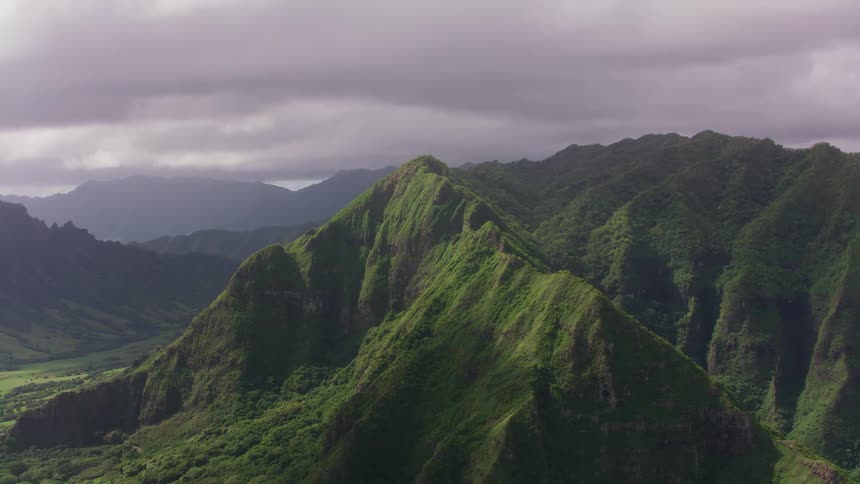 Green covered mountains under a cloudy sky