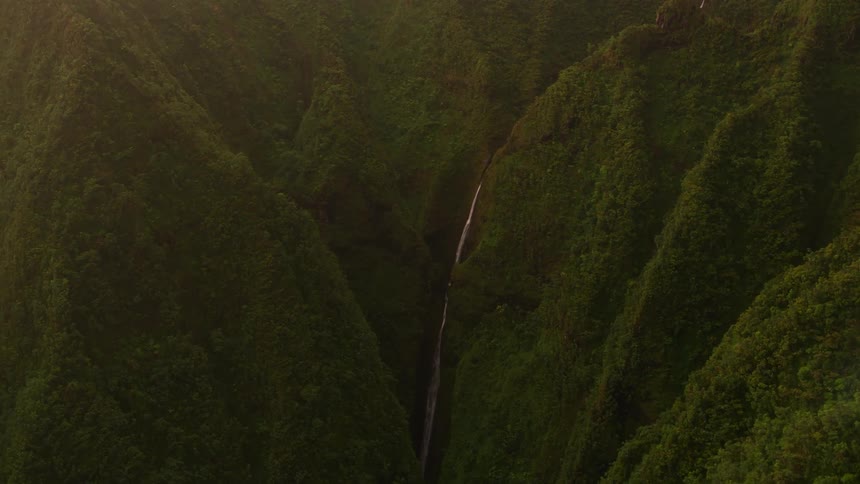 A waterfall is running off the green mountain