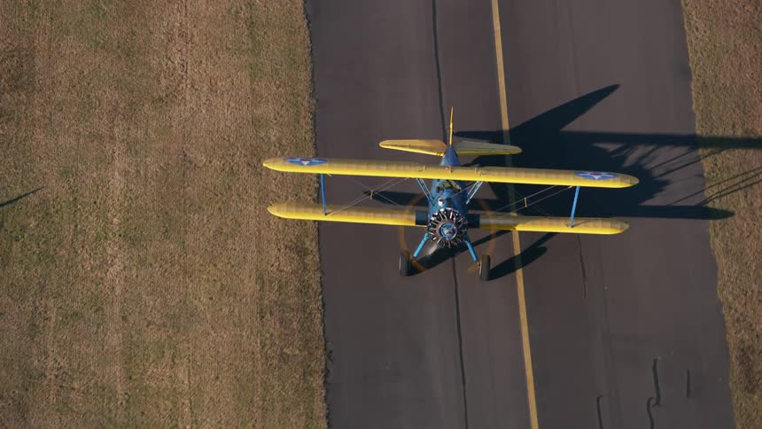 A biplane is traveling on a two lane road
