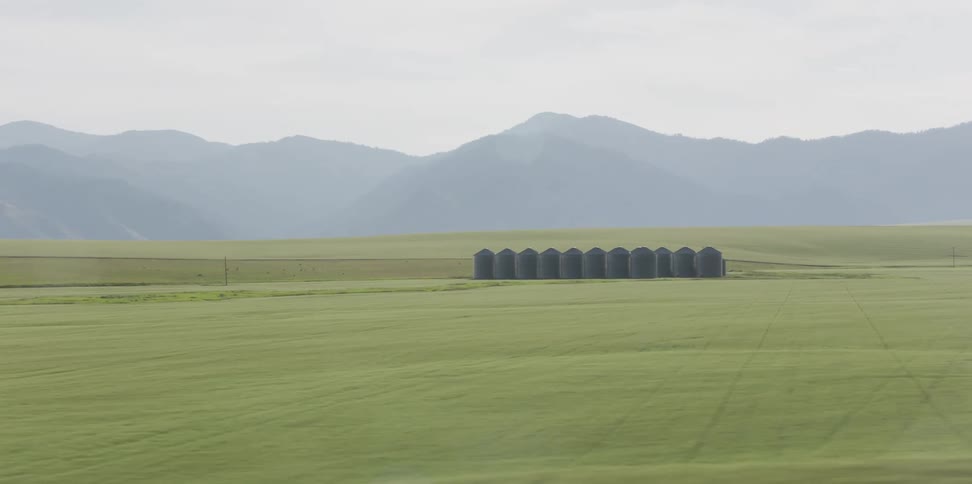 Aerial view of silos on the middle of green fields near the mountains