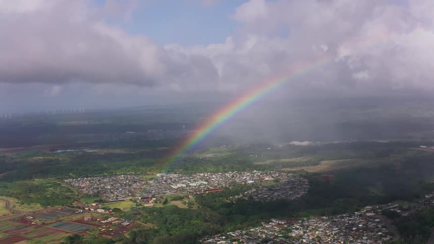 A rainbow has formed near some storm clouds in the sky