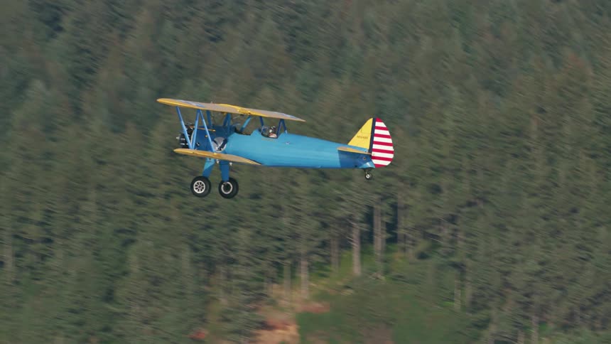 A small blue plane is flying through a mountain area