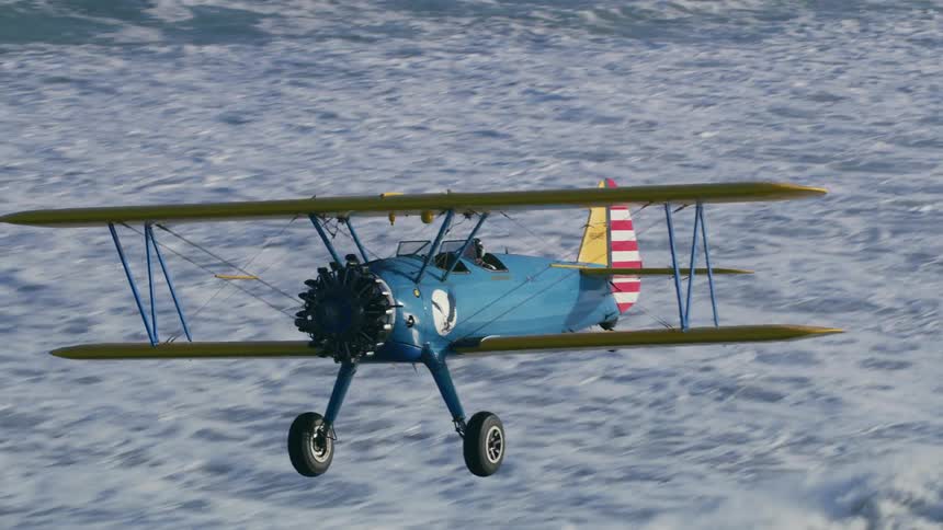 A biplane flies over snow covered ground