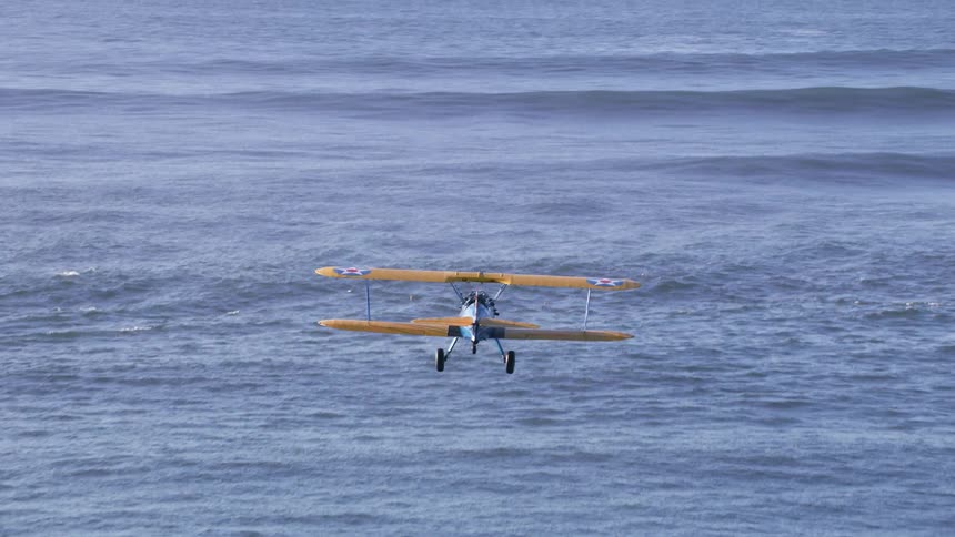 A plane glides past the ocean