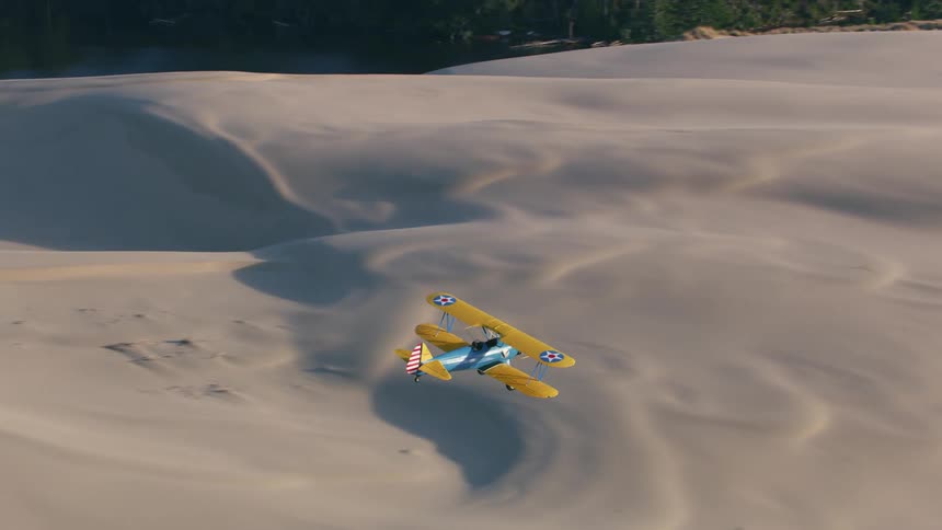 A plane flies over the dunes on the beach