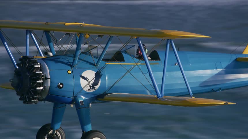 A man flies an airplane over a large body of water