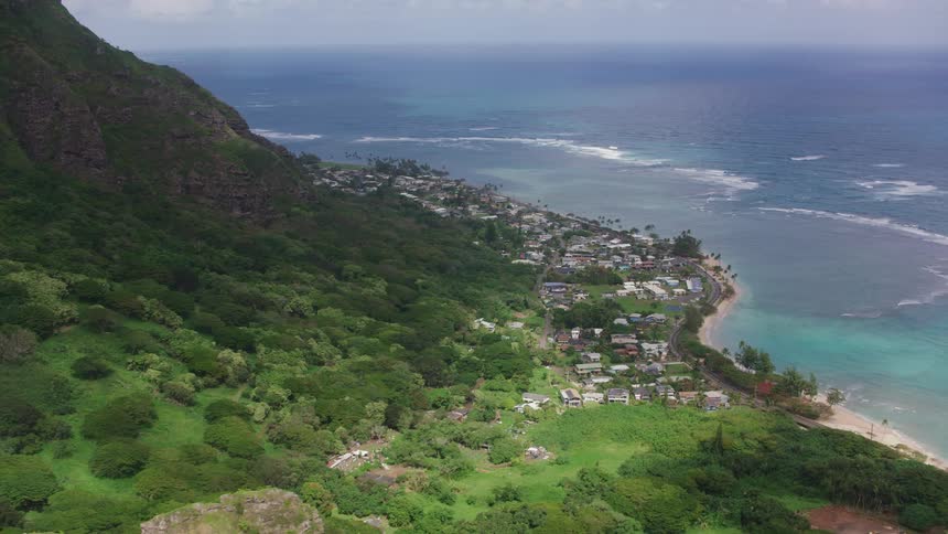 Highway parallels beach hugging town sitting between forested slope and ocean