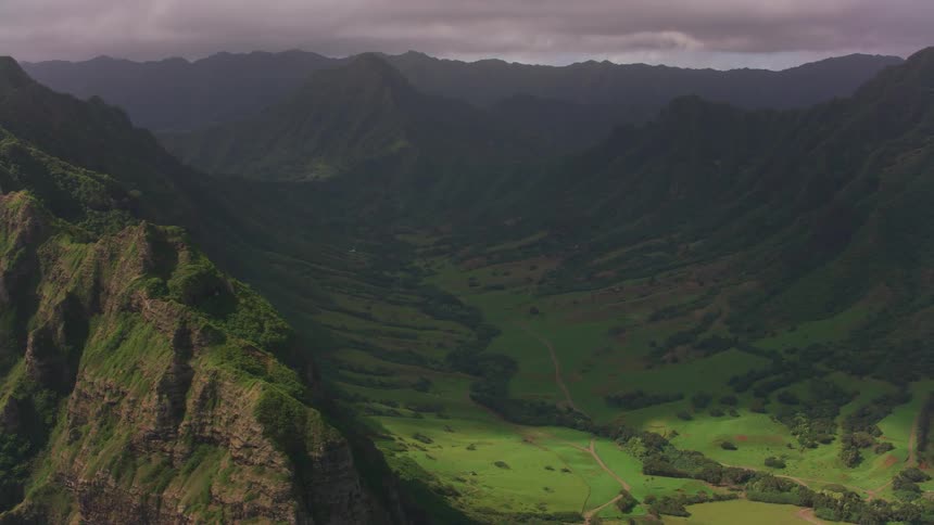 An aerial view of a mountainous landscape with a green valley on a cloudy day