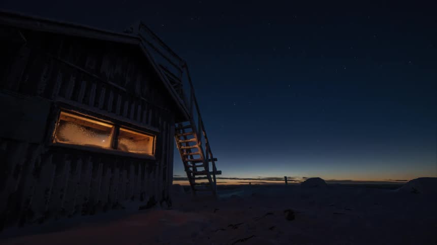 Sunset time lapse of a snowy wilderness cabin in Finland