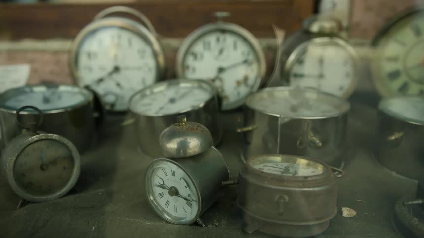 Several metal alarm clocks sit on a table