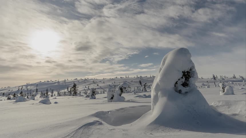 Clouds float over a snowy hillside in the wilderness