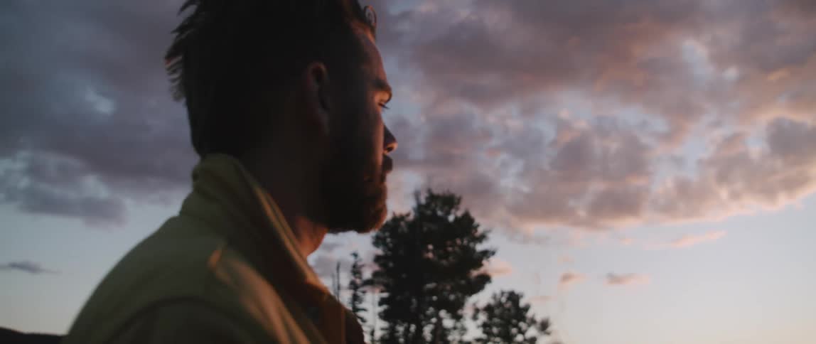 A man is smoking as he watches the sunset
