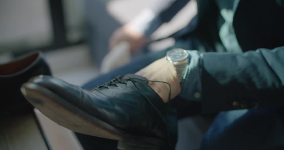 A man sits and polishes his shoe