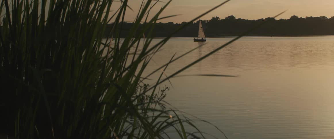 A small sailboat is traveling in the lake