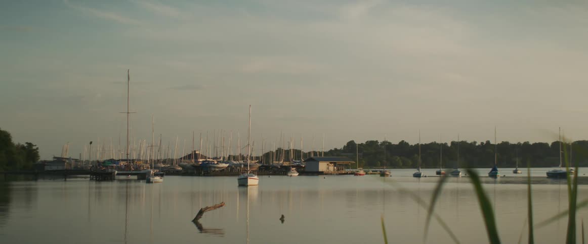 A lake with boats with trees the sky and clouds in the background
