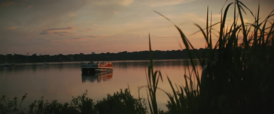 Boats float in a lake surrounded with tall grass
