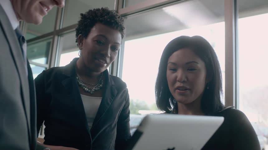 Three co-workers talk and look at a tablet