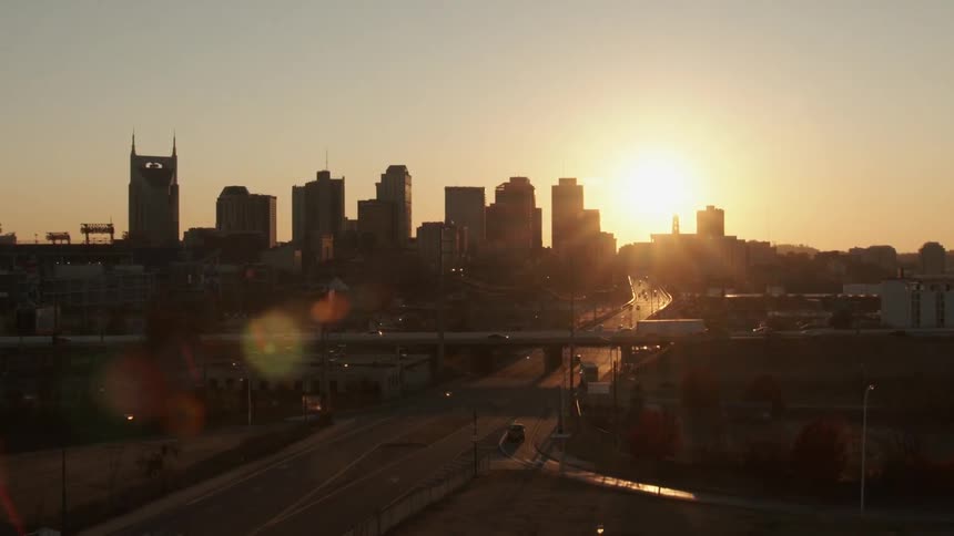 The sun sets behind a city