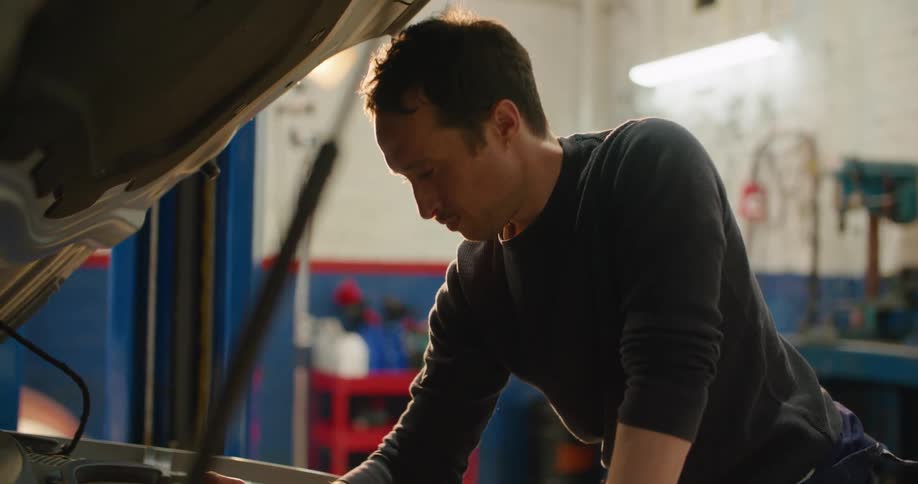 A man is working on the engine of the vehicle