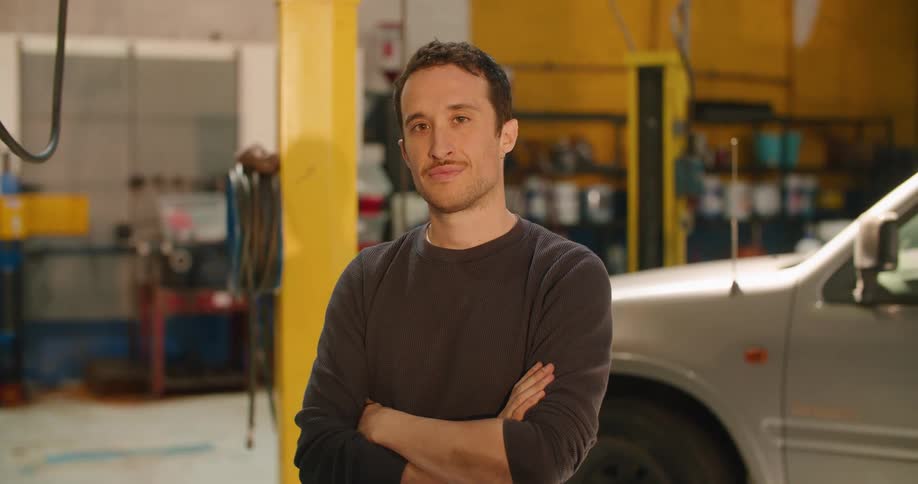 A male mechanic standing for a portrait in an auto body shop