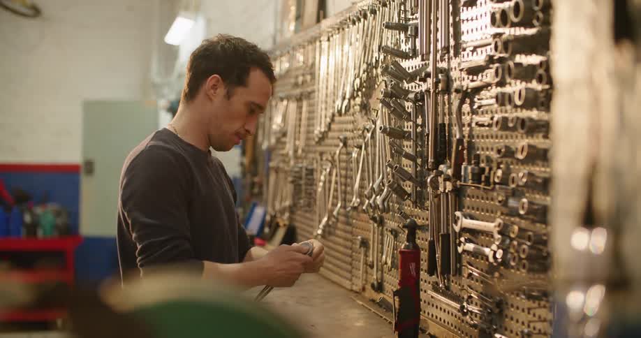A man grabs a socket wrench from the wall