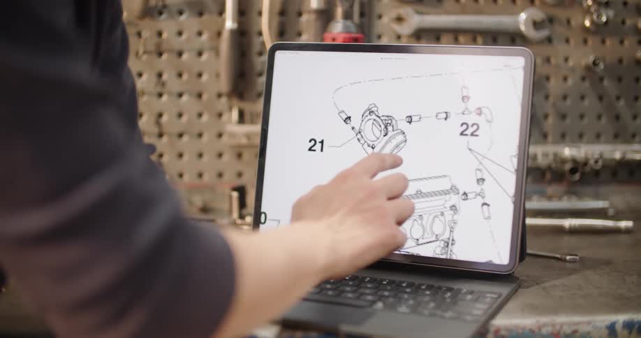 Man working in workshop adjusts parts diagram on touchable screen