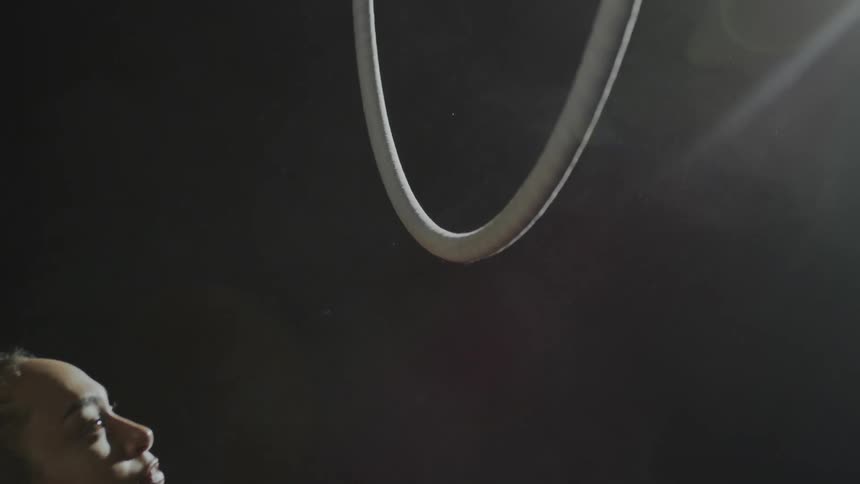 A gymnast applies rosin powder to a large hoop before grabbing on