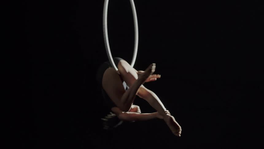A flexible acrobat spinning on a suspended hoop while performing tricks