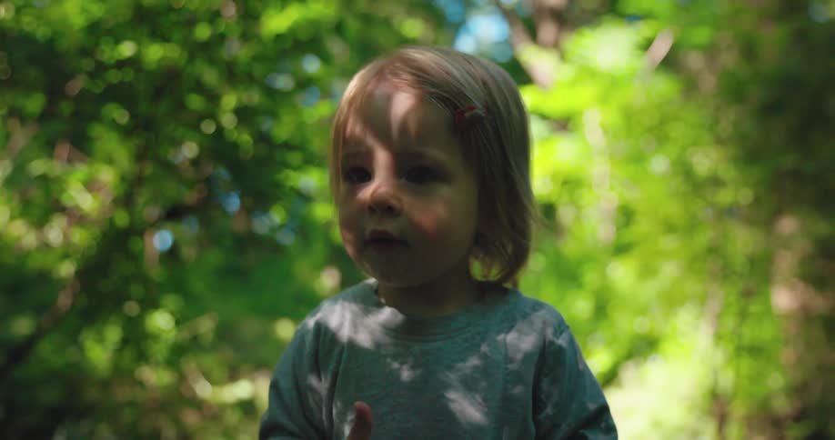 A kid standing in a foresty area