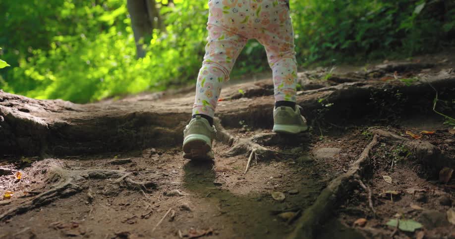 A child is walking over a root in the dirt