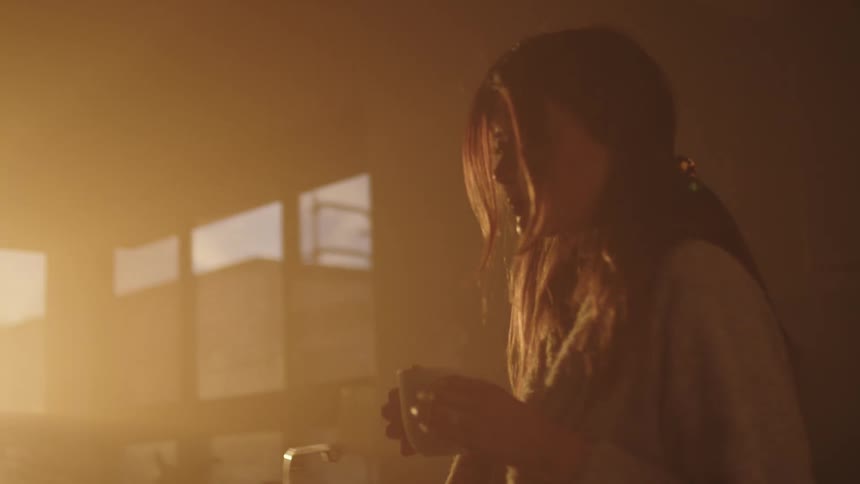 A woman walking out of a kitchen with a mug