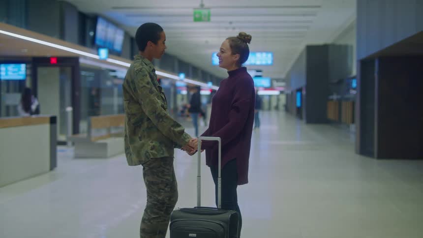 Two women greet each other and hold hands before walking away