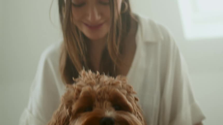 A young woman sits with her pet dog and vigorously rubs its neck