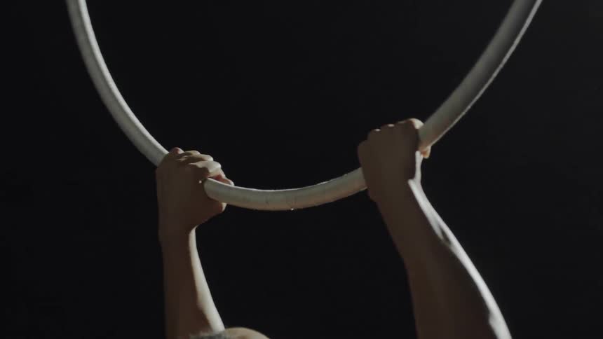 A woman is doing gymnastics on a hanging ring