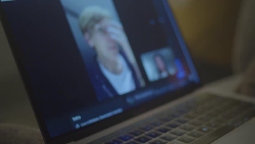 Group of people on a video call through a laptop over a desk