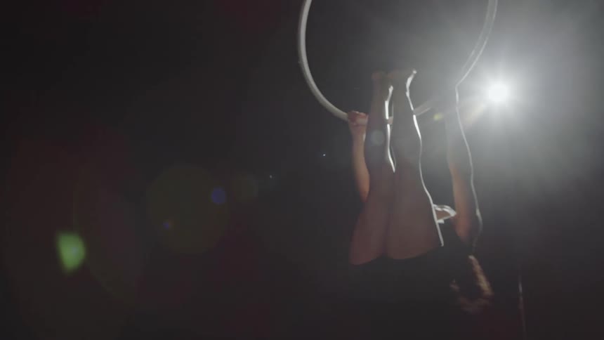 Strong muscular fit woman spinning on a ring hanging from the ceiling