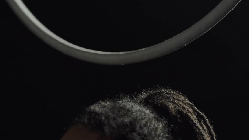 A womans hands release a spinning ring and she stands beneath it